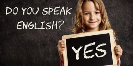 Dziecko z napisem "Yes" obok tablicy z hasłem "Do you speak English?"