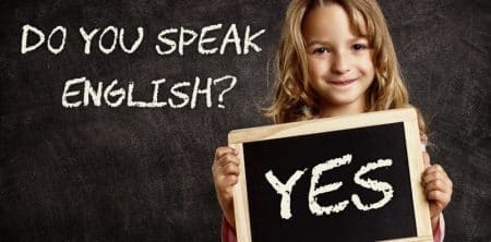 Dziecko z napisem "Yes" obok tablicy z hasłem "Do you speak English?"