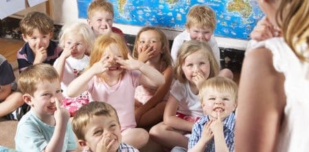 Grupa uśmiechniętych dzieci dotyka palcem nosa