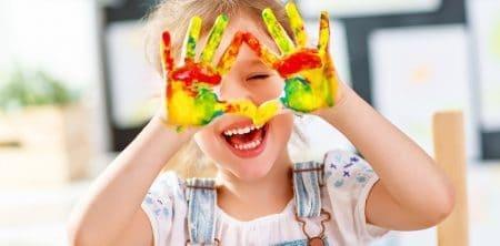 Uśmiechnięte dziecko z pomalowanymi na kolorowo dłońmi